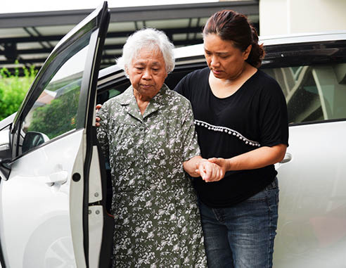 Caregiver help Asian elderly woman disability patient get in her car, medical concept.